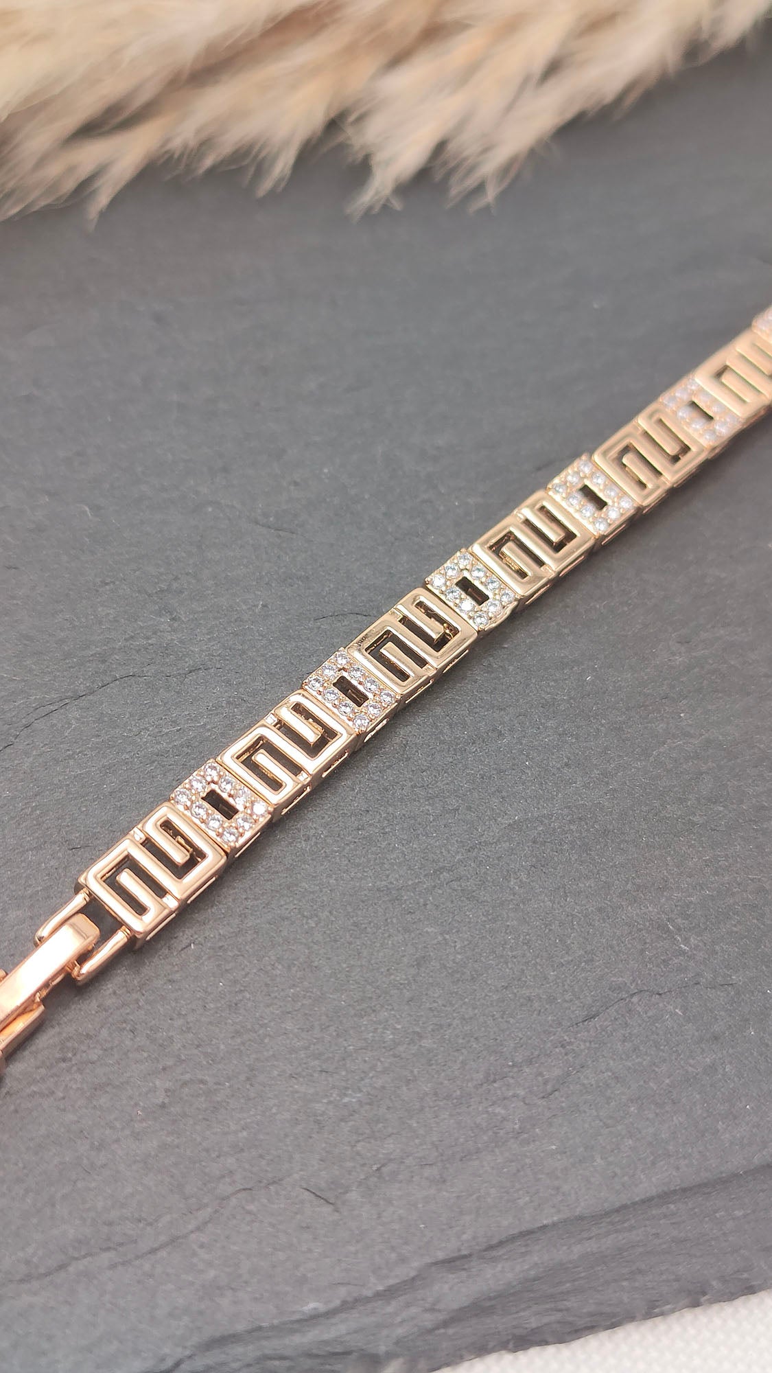 Nora Geometric Link Bracelet featuring a gold-tone geometric pattern with sparkling accents, displayed on a sleek slate background.