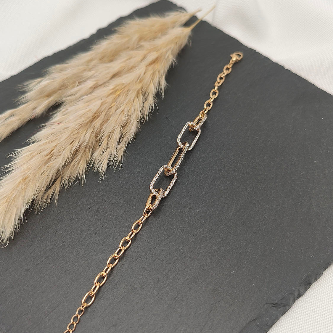 Cecilia Linked Pavé Bracelet featuring interlocking gold-tone links with pavé crystal accents, displayed on a slate background.