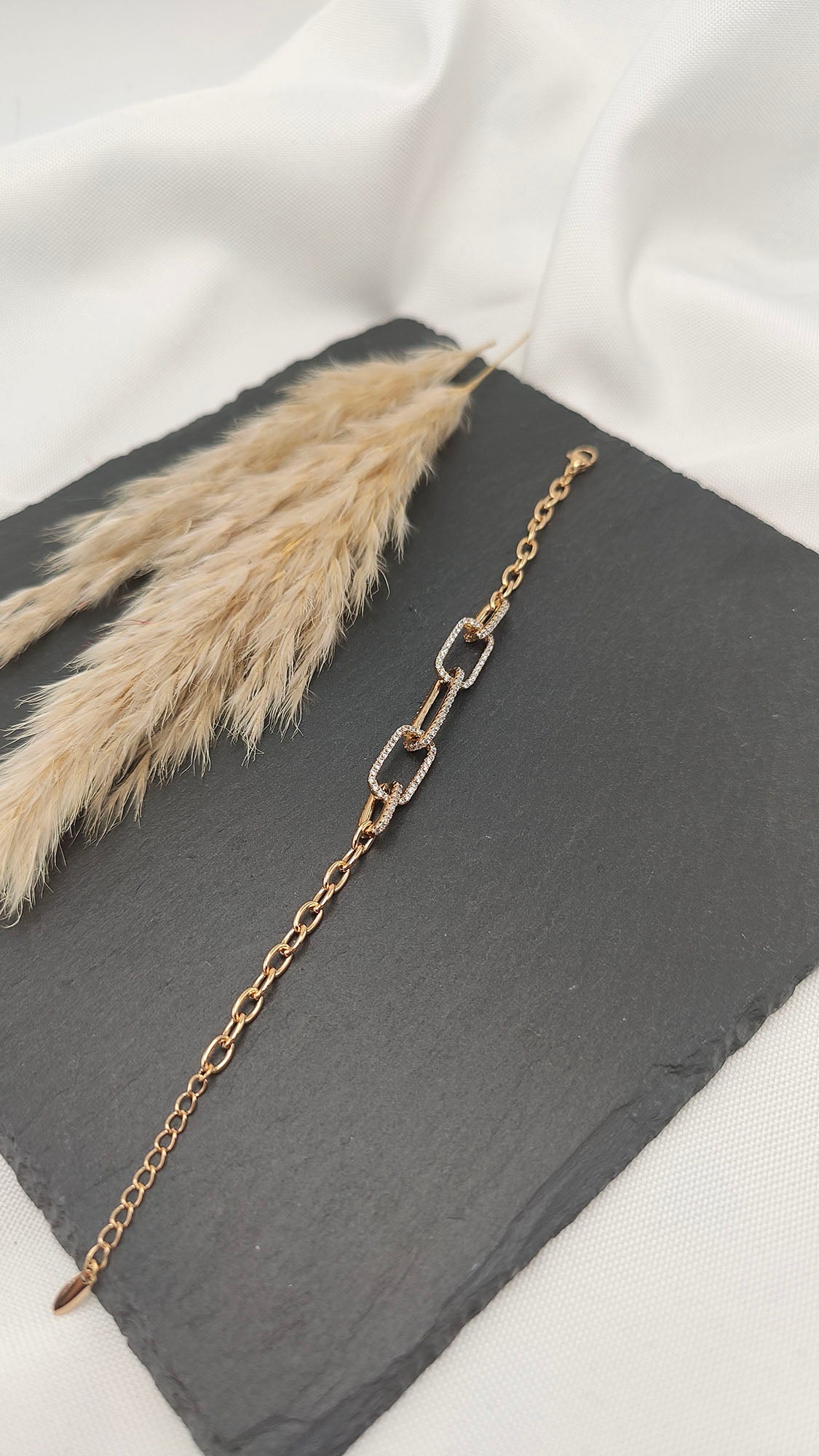 Cecilia Linked Pavé Bracelet featuring interlocking gold-tone links with pavé crystal accents, displayed on a slate background.